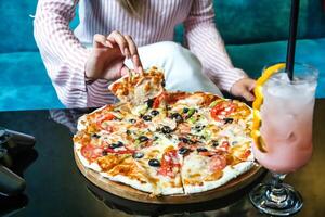 Woman Sitting at Table With Pizza and Drink photo