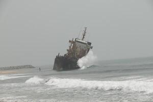 shipwreck against which the waves crash, cotonou, benin photo