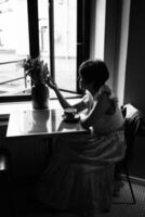 un niña con un corto Corte de pelo en un restaurante, negro y blanco foto en Clásico estilo