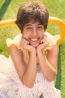 girl with a short haircut in a yellow dress on a sun drenched sports field in Copenhagen photo