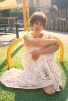 girl with a short haircut in a yellow dress on a sun drenched sports field in Copenhagen photo