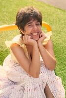 girl with a short haircut in a yellow dress on a sun drenched sports field in Copenhagen photo