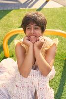 girl with a short haircut in a yellow dress on a sun drenched sports field in Copenhagen photo