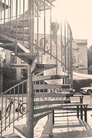 un niña con un corto Corte de pelo en un amarillo vestir en un iluminado por el sol espiral escalera en Copenhague foto