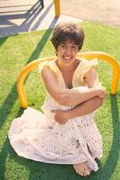 girl with a short haircut in a yellow dress on a sun drenched sports field in Copenhagen photo