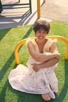 girl with a short haircut in a yellow dress on a sun drenched sports field in Copenhagen photo