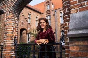 un niña en un rojo pana vestir con un abierto espalda camina mediante el calles de brujas en un otoño día foto