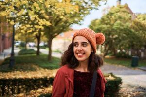 un niña en un sombrero con pompones camina el calles de brujas en un otoño día foto