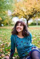 a girl in a dress with balloons lies on the ground covered with autumn leaves photo