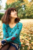 girl in a dress with balloons on a swing in an autumn garden photo