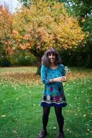 a girl in a dress with balloons is playing in the autumn garden photo