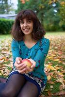 a girl in a dress with balloons lies on the ground covered with autumn leaves photo