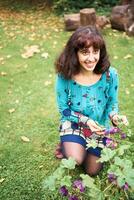 un niña en un vestir con globos mira a flores en el jardín foto