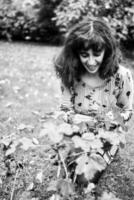 un niña en un vestir con globos mira a flores en el jardín foto