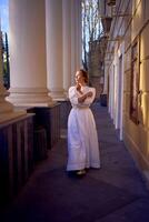 elegant middle age woman in white vintage dress near theater with antique colonnades photo