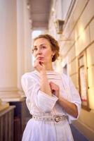 elegant middle age woman in white vintage dress near theater with antique colonnades photo