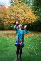 a girl in a dress with balloons is playing in the autumn garden photo