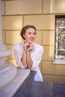 elegant middle age woman in white vintage dress near theater with antique colonnades photo