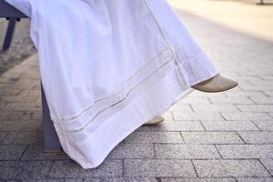 elegant middle age woman in a white vintage dress sitting on a bench in the morning city photo