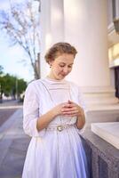 elegant middle age woman in white vintage dress near theater with antique colonnades photo