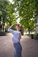 beautiful middle age woman in 70s, 80s style clothes stretches after work on a sun drenched alley photo