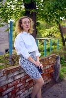 middle age woman in 70s, 80s style clothes with a coffee stain on her blouse in front of gray houses of the 70s photo