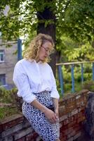 middle age woman in 70s, 80s style clothes with a coffee stain on her blouse in front of gray houses of the 70s photo