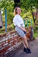 middle age woman in 70s, 80s style clothes with a coffee stain on her blouse in front of gray houses of the 70s photo