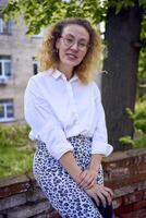 middle age woman in 70s, 80s style clothes with a coffee stain on her blouse in front of gray houses of the 70s photo