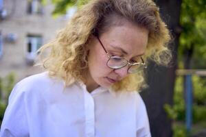 middle age woman in 70s, 80s style clothes with a coffee stain on her blouse in front of gray houses of the 70s photo