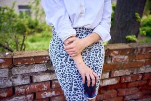 middle age woman in 70s, 80s style clothes with a coffee stain on her blouse in front of gray houses of the 70s photo