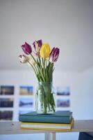 bouquet of multicolored tulips in a transparent jar in the interior photo