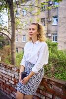 middle age woman in 70s, 80s style clothes with a coffee stain on her blouse in front of gray houses of the 70s photo