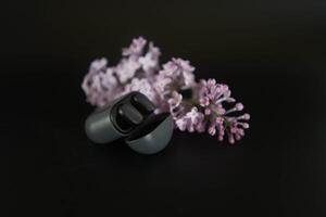 a case with headphones on the background of a lilac branch photo