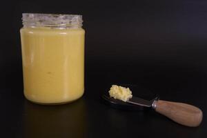 butter ghee in a transparent jar with homemade bread on a black background photo