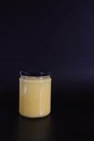 butter ghee in a transparent jar with homemade bread on a black background photo