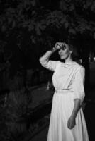 elegant middle age woman in a white vintage dress against the background of historical buildings in the morning light photo