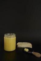 butter ghee in a transparent jar with homemade bread on a black background photo