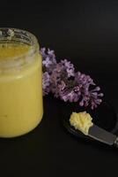 butter ghee in a transparent jar with homemade bread on a black background photo