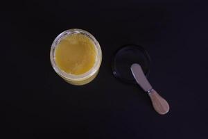 butter ghee in a transparent jar with homemade bread on a black background photo