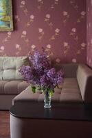 un ramo de flores de lilas en un cristal florero en el interior foto