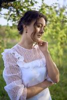 beautiful woman in white vintage dress with train in spring garden at sunset photo