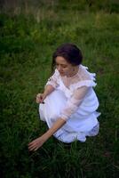 beautiful woman in white vintage dress with train in spring garden at sunset photo