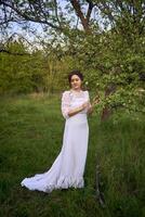 beautiful woman in white vintage dress with train in spring garden at sunset photo