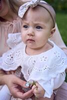 un bebé niña sostiene un flor en su manos en su de la madre brazos foto