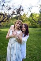 a mother and her teenage daughter are hugging and playing in the garden photo