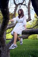 Adolescente niña en un blanco vestir en un árbol foto