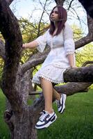 Adolescente niña en un blanco vestir en un árbol foto