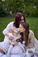 sisters of different ages hug each other tenderly on a picnic in the garden photo