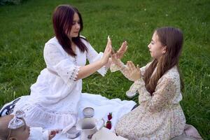 sisters of different ages hug each other tenderly on a picnic in the garden photo